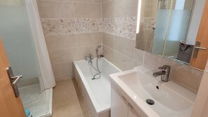 Un bagno con vasca, lavandino e zona doccia.