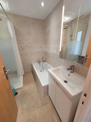A bathroom with a bathtub, a sink, and a shower area. - Centre Ville, t2 pour 4 N31 (La Grande-Motte)