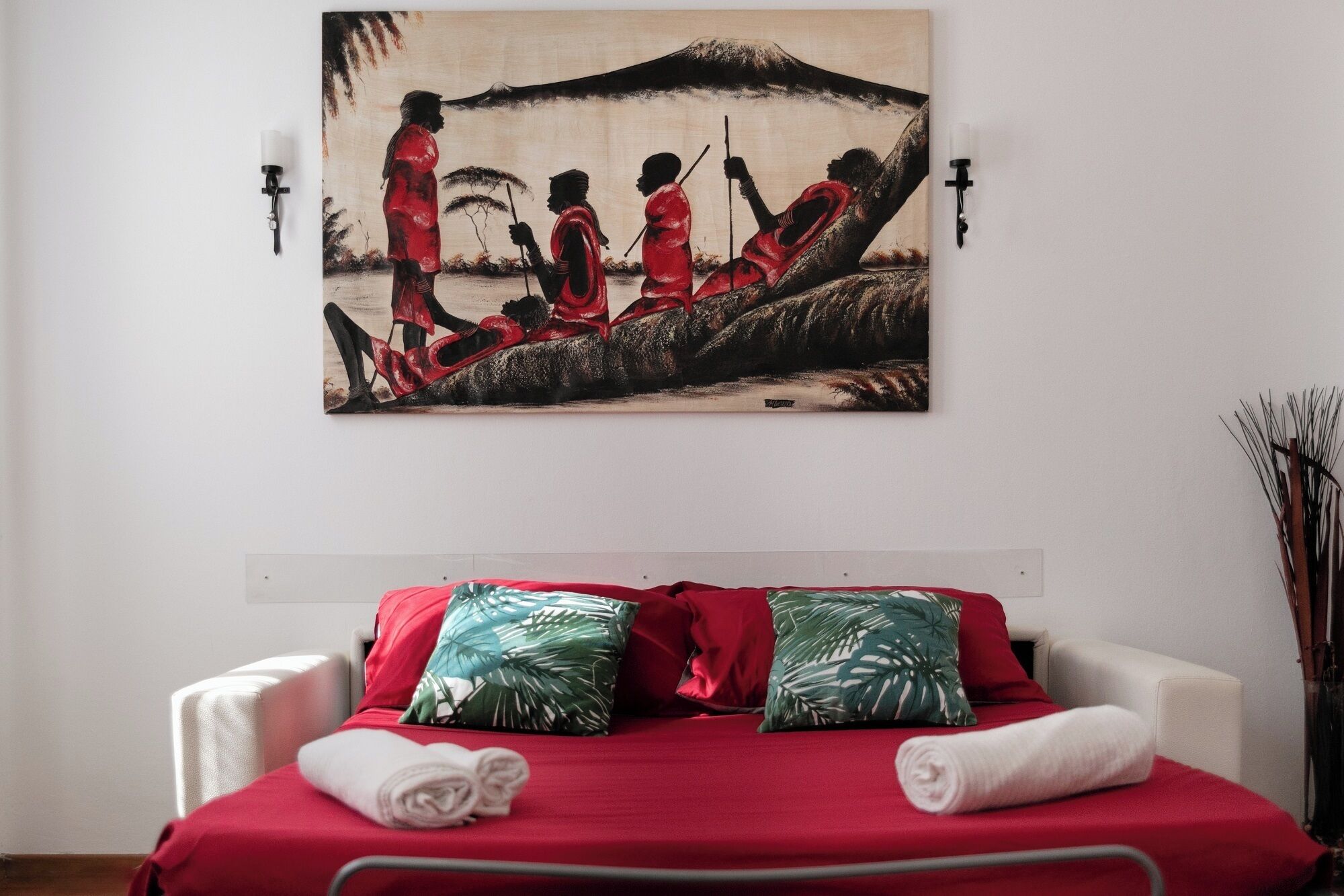 Quarto de hotel com cama, almofadas e um quadro na parede.