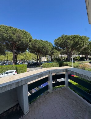 A paved walkway with a metal railing, surrounded by trees and parked cars. - Secteur Golf, t2 pour 4 personnes N52 (La Grande-Motte)