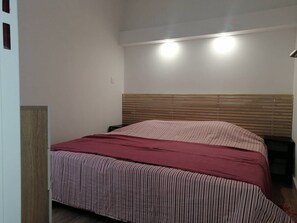Ein Schlafzimmer mit einem Holzkopfteil, einer gestreiften Bettdecke und zwei Nachttischlampen.