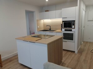 Eine kompakte Küche mit Kochinsel, integriertem Backofen, Mikrowelle und Spüle.