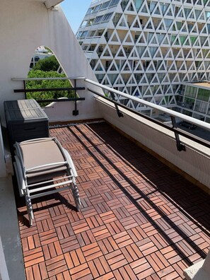 Eine Dachterrasse mit einem gemusterten Boden, einer Liege und einem Geländer.