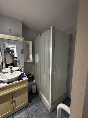Et badeværelse med dobbelt vaskemøbel, et spejl, en bruseniche og et toilet.