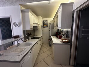 A compact kitchen with white cabinets, a sink, and a tiled backsplash. - Le temple du soleil, proche plage N76 (La Grande-Motte)