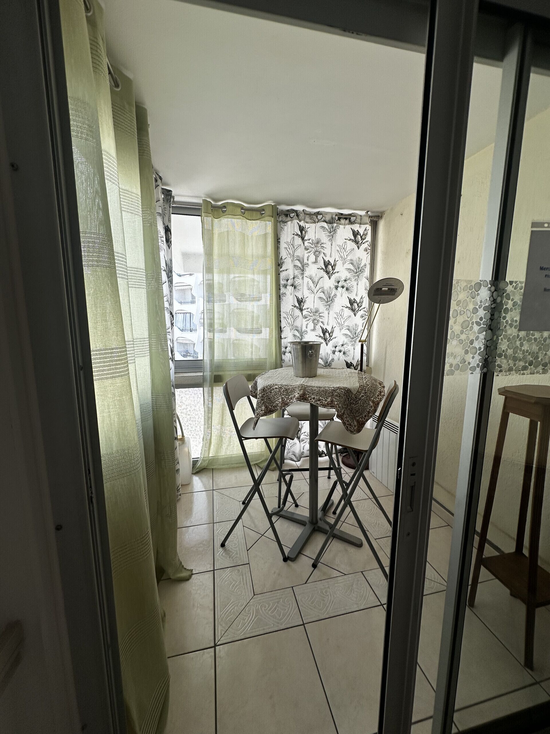 A room with a dining table, chairs, a window with curtains, and a tiled floor.