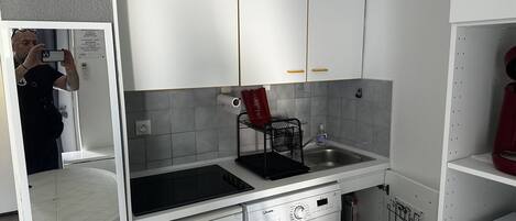 Una cocina compacta con lavadora, lavaplatos y un reloj en la pared.