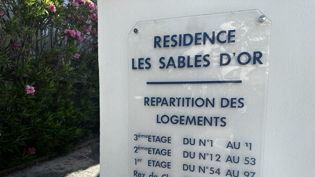 En skylt med texten ”RESIDENCE LES SABLES D’OR” och ”REPARTITION DES LOGEMENTS”, som anger platsen och fördelningen av lägenheterna.