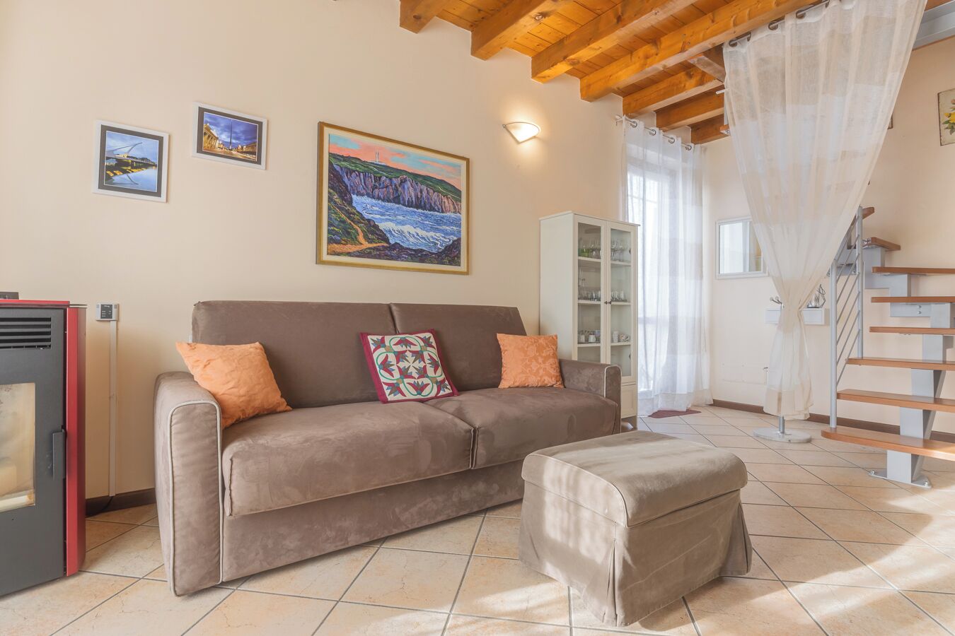 A living room with a sofa, ottoman, and a painting on the wall.