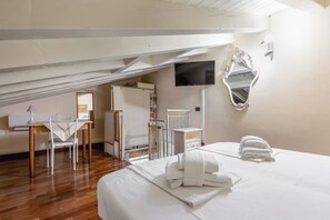 Ein Hotelzimmer mit Bett, Schreibtisch, Sessel, Fernseher und Spiegel.