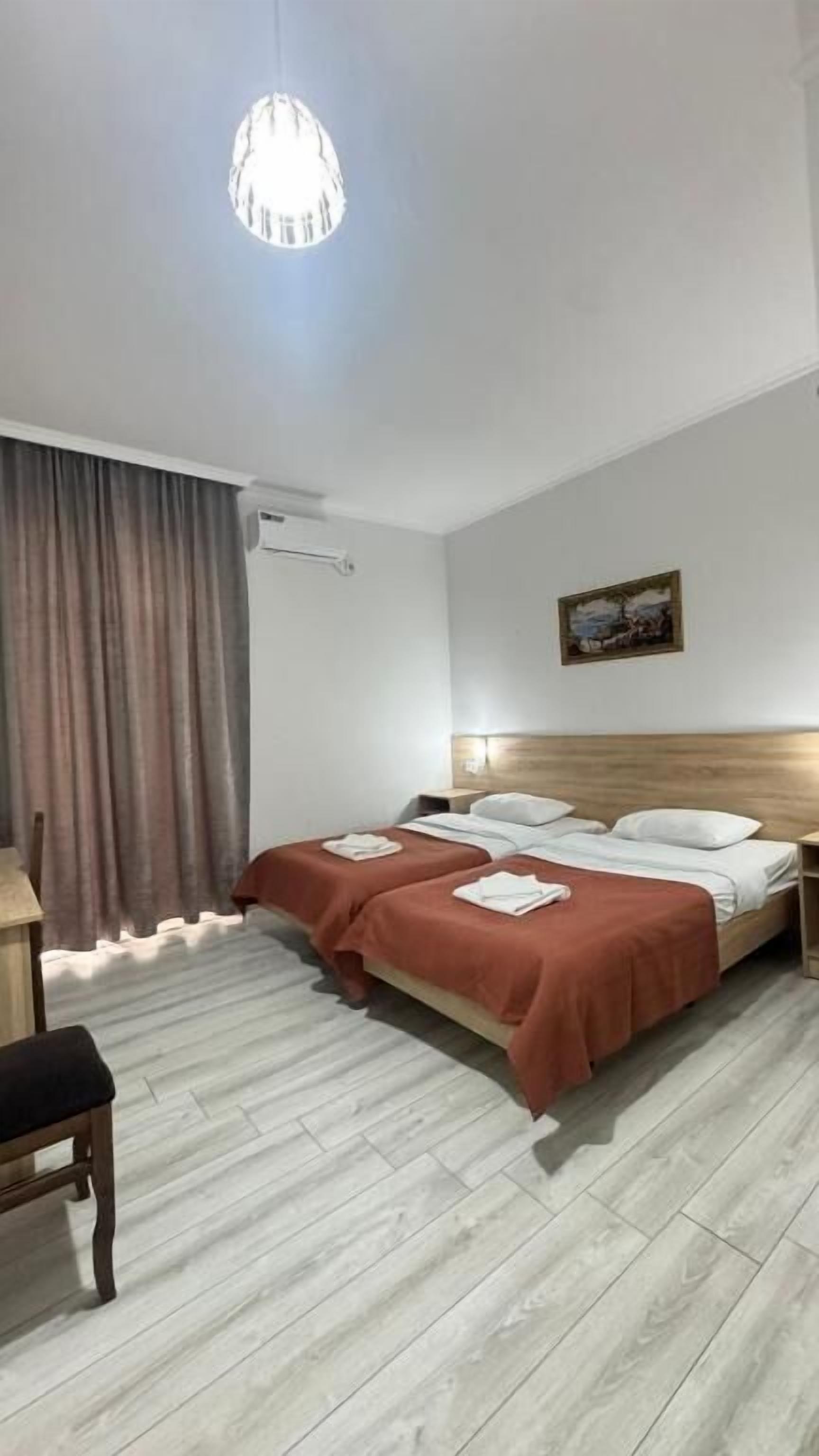 Una habitación de hotel con dos camas, cabecera de madera, un escritorio y una silla.