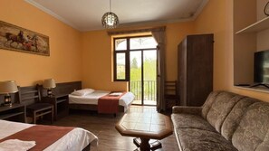 A hotel room with two beds, a sofa, a table, a TV, and a balcony with a view. - Hotel Giorgi (Tskaltubo)