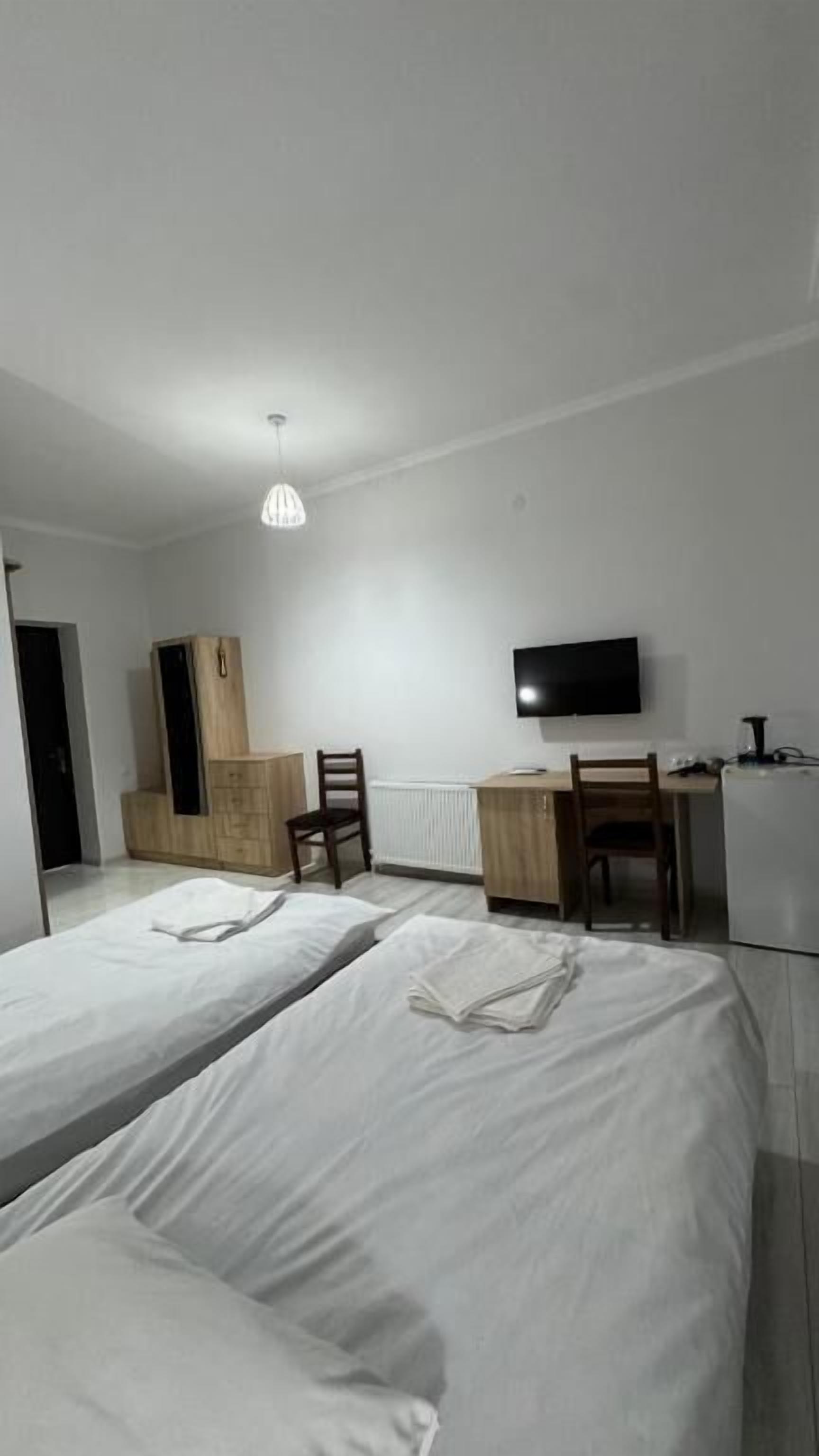 Una habitación de hotel con dos camas, un escritorio, una silla, un televisor y un radiador.