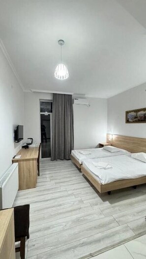 Habitación de hotel con cama, escritorio, silla y lámpara colgante.