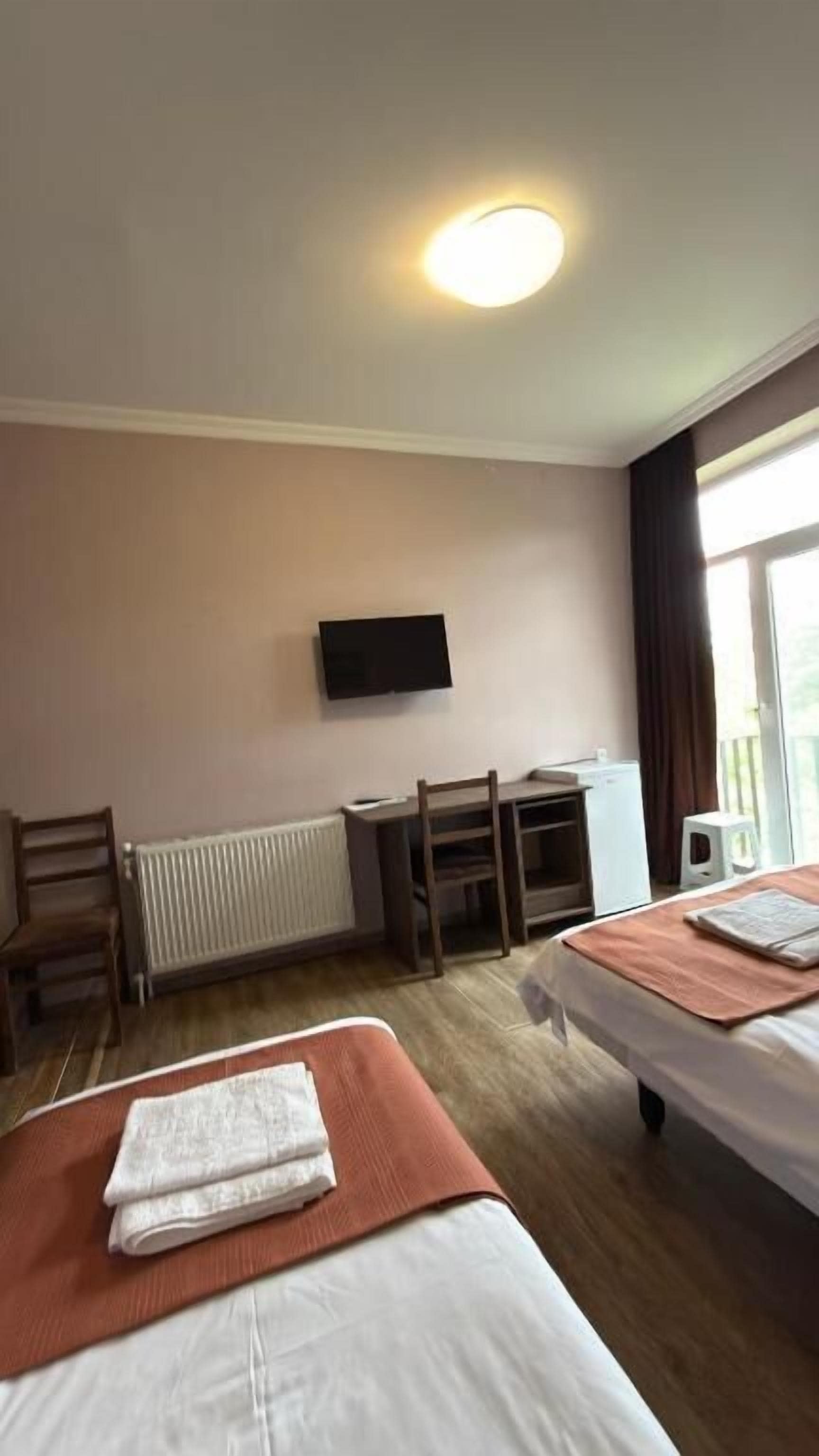 Una habitación de hotel con dos camas, un escritorio, una silla, un televisor y una ventana.