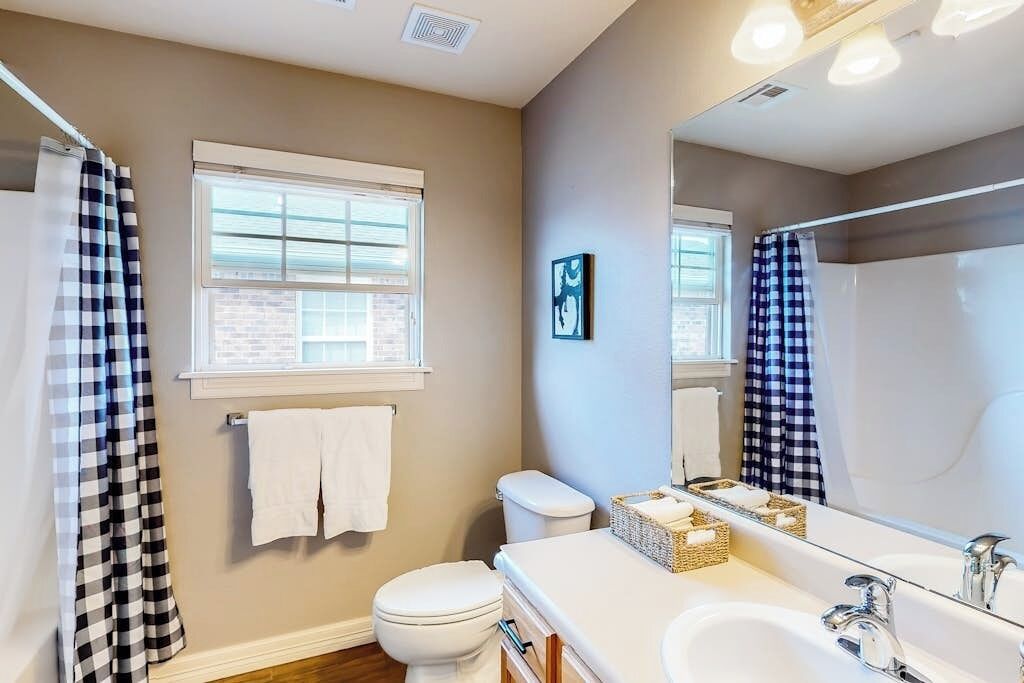 A bathroom with a toilet, a sink, a mirror, and a shower area.