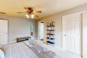 A bedroom with a bed, a bench, a ceiling fan, and a bookshelf. - The Brick Beauty | Dog-Friendly & Fenced Yard (Bentonville)