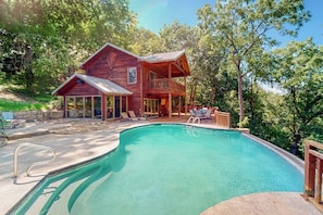 A wooden cabin with a swimming pool, surrounded by trees. - Lakefront 6BR with infinity pool, sauna & kayaks (Rogers)
