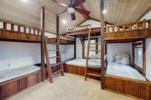 Ein Zimmer mit Etagenbetten, Holzbalken, Deckenventilator und einem Fenster.