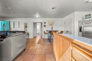 Een moderne keuken met een houten aanrecht, een roestvrijstalen koelkast en een eethoek met stoelen.