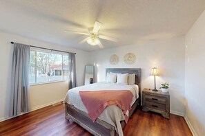 A bedroom with a bed, a nightstand, a ceiling fan, and a window with curtains. - 4BR Spacious Lakefront Retreat with Game Room (Hot Springs)