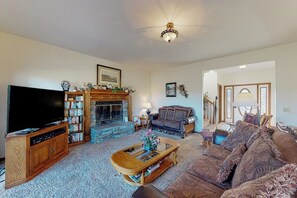 A living room with a fireplace, a television, a bookshelf, and a sofa. - 4BR Golf Course View Dog Friendly (Holiday Island)