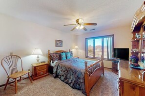 A bedroom with a bed, a chair, a nightstand, a TV, and a window with a view. - 4BR Golf Course View Dog Friendly (Holiday Island)