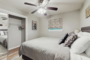 A bedroom with a bed, a ceiling fan, a wardrobe, and a window with a view. - 3BR Inviting woodland retreat - direct bike trail (Bella Vista)