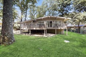 A two-story house with a balcony, surrounded by trees and a well-maintained lawn. - 3BR Inviting woodland retreat - direct bike trail (Bella Vista)