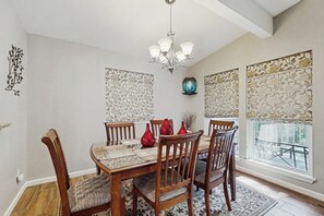 Een eetkamer met een houten tafel, stoelen en een kroonluchter.