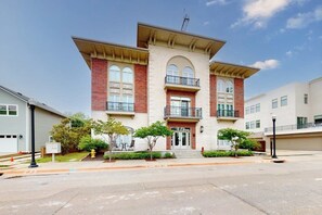 A multi-story residential building with a central entrance, balconies, and a fire hydrant in the foreground. - Downtown Bentonville Condo - Secure Bike Storage (Bentonville)