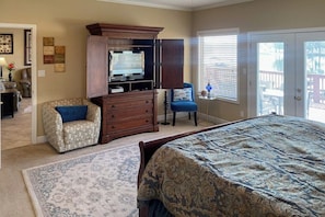 A bedroom with a bed, dresser, chair, and a television. - 2BR Serene lakefront condo with stunning views (Hot Springs)