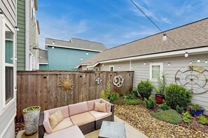 A backyard with a wooden fence, a pink sofa, and a small garden area. - Wander Bentonville | Walkable & Dog-Friendly (Bentonville)
