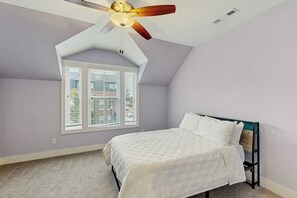 Una camera da letto con un letto, una ventola a soffitto, una finestra e vista all'esterno.