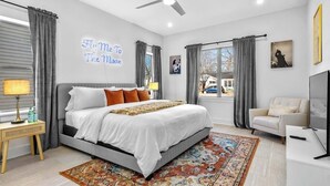 Une chambre moderne avec un grand lit, un ventilateur de plafond, une télévision et une vue sur l’extérieur.