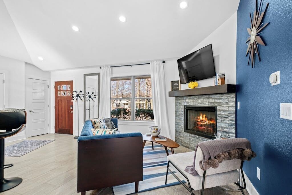 A living room with a fireplace, a television, and a view of the outside.
