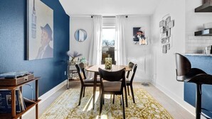 Un coin repas avec une table ronde et des chaises, une table basse et une vue par la fenêtre.