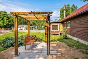 A wooden pergola with a bench, a house, and a grassy area. - Spacious 4BR - Firepit - Garage Parking - W&D (Bentonville)