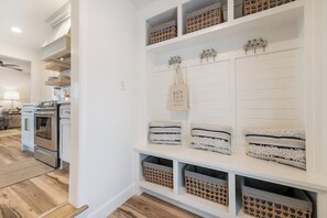 A kitchen with white cabinetry, a built-in oven, and a dining area with a table and chairs. - B Street Bungalow | Bike-In/Bike-Out & Game Room (Bentonville)