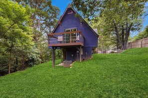 A house with a steeply pitched roof, a balcony with a metal railing, and a wooden deck. - 2BR dog-friendly cottage with spa & boat parking (Rogers)