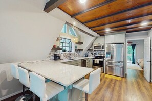 A kitchen with a white countertop, stainless steel appliances, and a wooden ceiling. - 2BR dog-friendly cottage with spa & boat parking (Rogers)