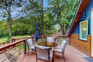 Eine Terrasse mit einem runden Tisch und Stühlen, umgeben von einem Holzboden und Bäumen.