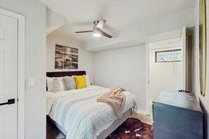 Ein Schlafzimmer mit Bett, Deckenventilator, Fenster und Tür.