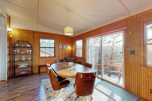 A wooden-paneled room with a large round table, chairs, a bookshelf, and a sliding glass door to a deck. - Quiet 2BR Lakeview Dog Friendly - Deck - Firepit (Eureka Springs)