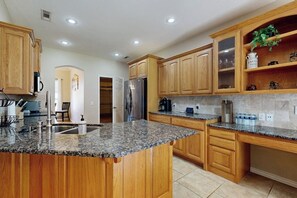 A modern kitchen with granite countertops, wooden cabinets, and stainless steel appliances.