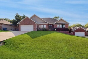 A single-story house with a garage, a well-maintained lawn, and a clear sky.