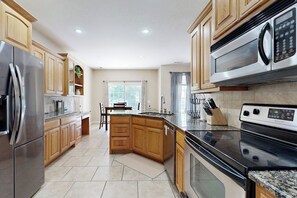 A modern kitchen with stainless steel appliances, wooden cabinets, and a granite countertop. - Bella Vista Retreat | Bike-In/Out & Game Garage (Bella Vista)