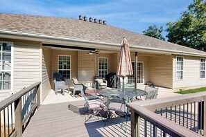 A covered patio with outdoor furniture, a grill, and a ceiling fan.