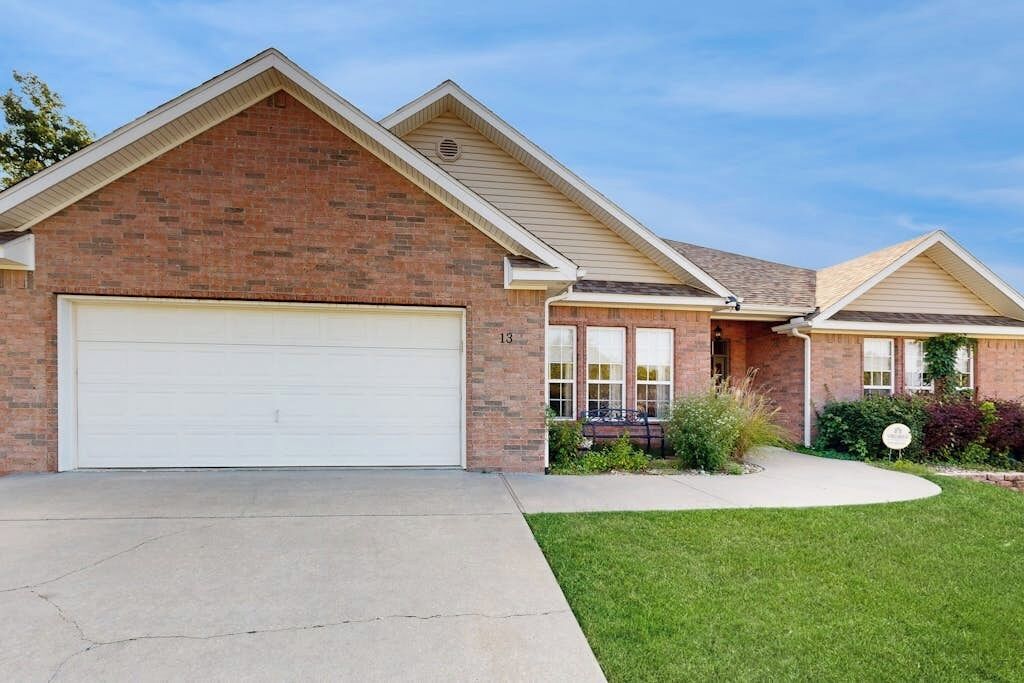 A two-story brick house with a garage, a front yard, and a driveway.
