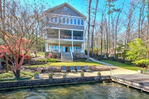 A two-story building with a balcony, a dock, and a landscaped garden with chairs. - 5BR Lakefront home - Dock, 2 kitchens, pool table (Hot Springs)